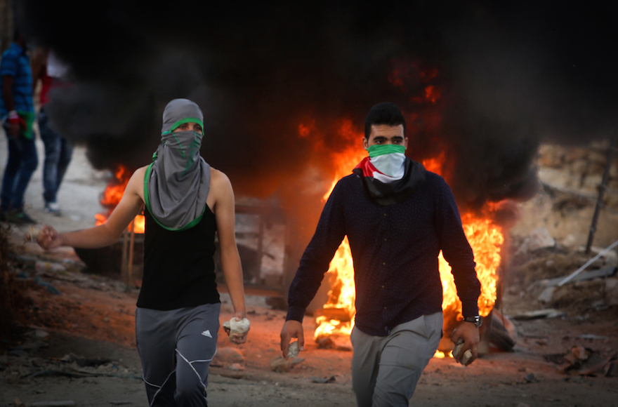 Palestinian protesters throw stones and burn tires during  clashes with Israeli security forces over the Al-Aqsa mosque compound, close to the Israeli manned checkpoint of Hezma in the West Bank, on September 30, 2015. The compound has been the scene of repeated clashes in recent weeks, provoking international calls for calm at the highly sensitive site which is the third holiest in Islam but is also known to Jews as the Temple Mount, the most sacred in Judaism. Photo by FLASH90