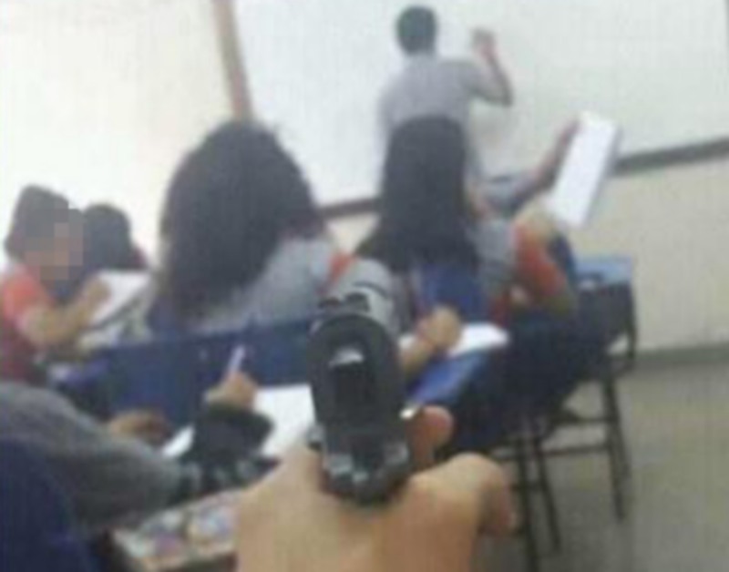 Imagem mostra aluno apontando arma para professor dentro de sala de aula (Foto: Reprodução/Facebook)