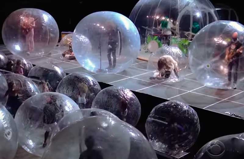 The Flaming Lips tocou um de seus hits mais conhechidos, 'Race for the Prize' enquanto usavam máscaras e luvas dentro das bolhas (Foto: CBS/Reproduçao)
