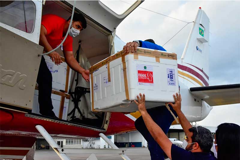 Caixa com vacina é embarcada em avião para o interior (Foto: Mauro Neto/Secom)