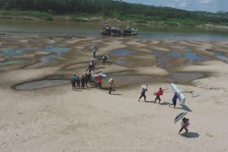 Moradores carregam produtos no leito seco do rio em Envira (Foto: Defesa Civil/Envira/Divulgação)