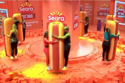 Na Prova do Líder, participantes ficam segurando hot dog gigante (Imagem: Globoplay/Reprodução)