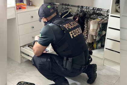 Agente federal inspeciona documentos em casa de suspeito em Manaus (Foto: PF/Divulgação)
