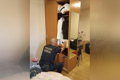 Agente da PF inspeciona cofre em casa de suspeito: combate ao tráfico de mulheres (Foto: PF/Divulgação)