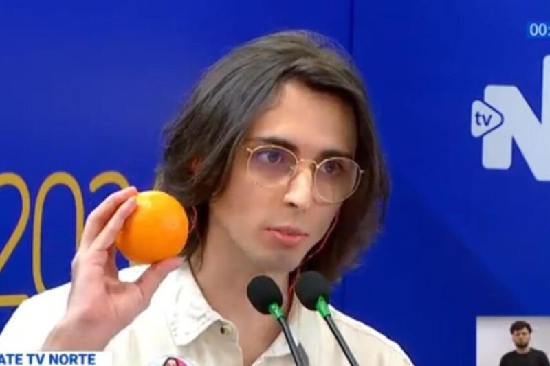 No debate, Amom disse que daria um presente para Wilker e mostrou uma laranja (Imagens: Reprodução/TV Norte) 