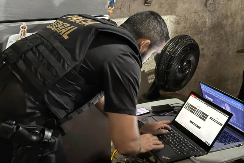 Agente federal inspeciona computador de suspeito de abuso sexual infantil (Foto: PF/Divulgação)