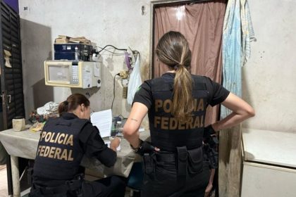 Policiais da PF analisam documentos e computador na casa do suspeito (Foto: Divulgação/PF)
