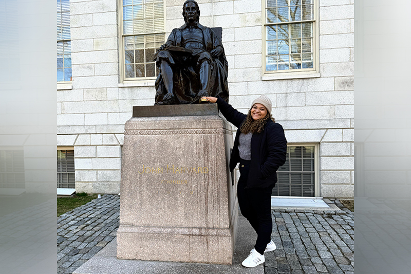 Silvana Nascimento na estátua de John Harvard, fundador da universidade: apreensão com decisão de Trump (Foto: Acervo Pessoal/Divulgação)