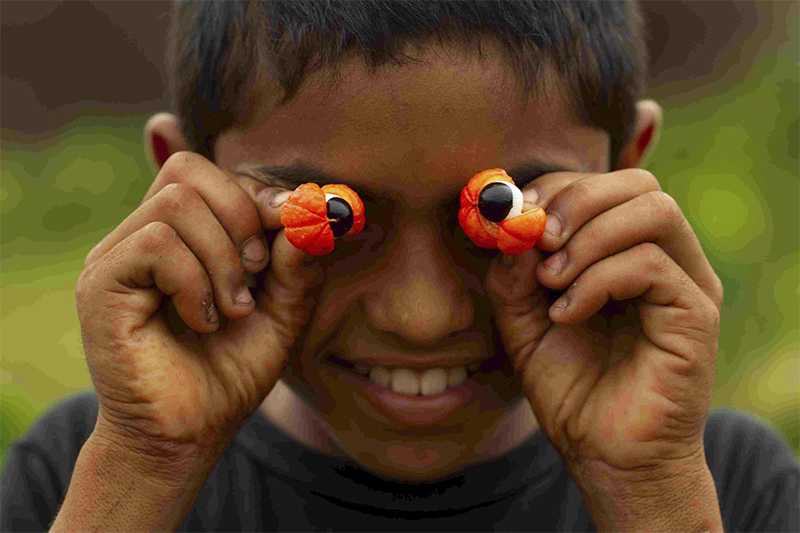 Menino brinca com frutos do guaraná: olhos amazônicos (Foto: Bruno Kelly/Divulgação)