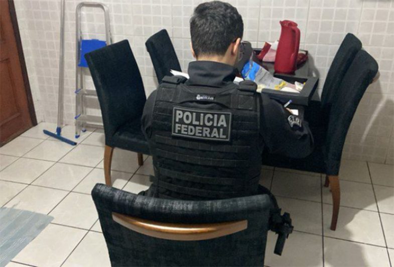 Agente federal inspeciona material em casa de suspeito (Foto: PF/Divulgação)