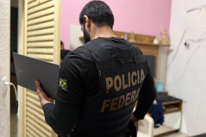 Agente federal inspeciona computador apreendido na operação (Foto: PF/Divulgação)