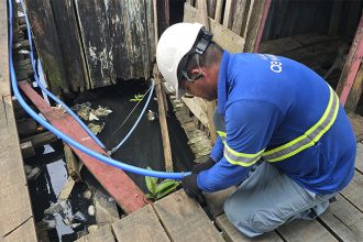 Técnico da Águas de Manaus pendura tubulação de água em passarela em área sujeita a alagação em Manaus (Foto: Águas de Manaus/Divulgação)