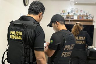 Agentes federais inspecionam documentos em casa de suspeito de fraude (Foto: PF/Divulgação)