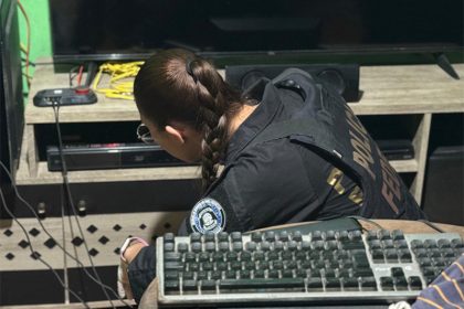 Agente federal inspeciona computador e vídeo de suspeito de abuso sexual infantil (Foto: PF/Divulgação)