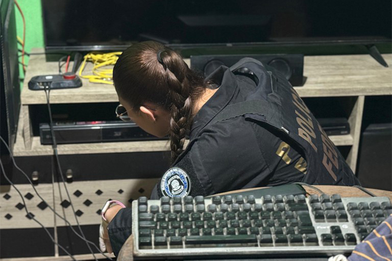 Agente federal inspeciona computador e vídeo de suspeito de abuso sexual infantil (Foto: PF/Divulgação)