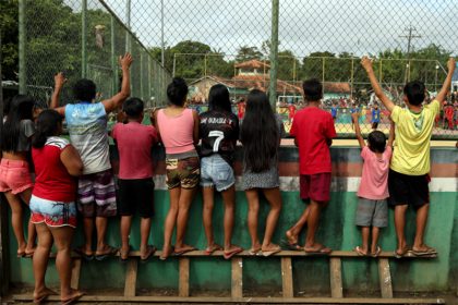 Crianças e adolescentes indígenas usam escada para ver partida de futebol: segunda melhor sobre o esporte (Foto: Michael Dantas/Museu do Futebol)
