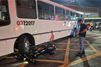 Moto ficou quase embaixo do ônibus; motociclista foi socorrido com ferimentos (Foto: WhatsApp/Divulgação)
