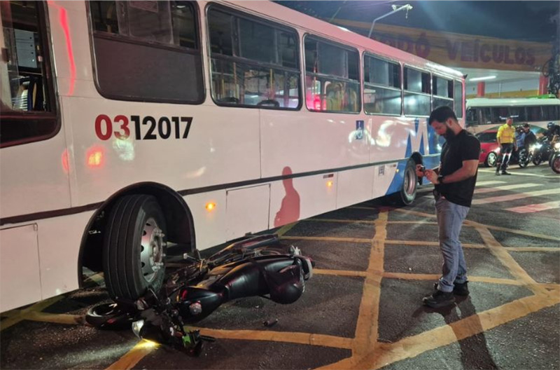 Moto ficou quase embaixo do ônibus; motociclista foi socorrido com ferimentos (Foto: WhatsApp/Divulgação)