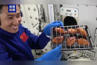 Astronauta mostra asas de frango assadas na estação espacial Tiangong (Imagem: Reprodução/YouTube/China Central Television)
