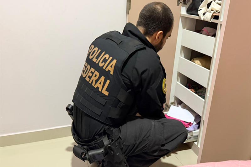Agente federal recolhe documentos em casa de investigado (Foto: PF/Divulgação)
