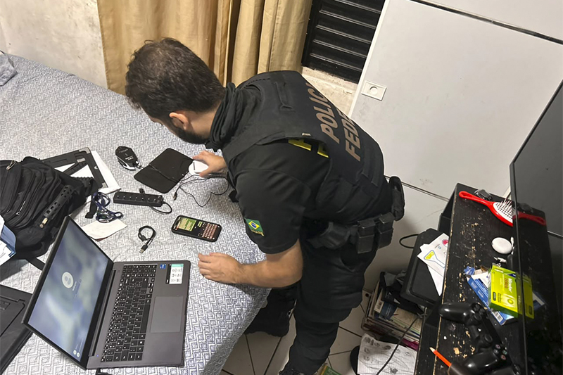 Agente federal inspeciona computador em casa de suspeito em Manicoré (Foto: PF/Divulgação)