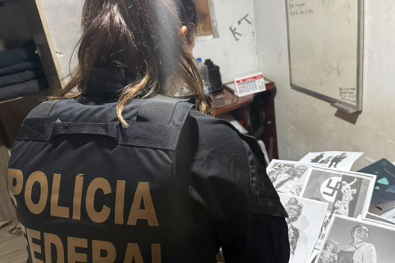 Agente federal inspeciona documentos e fotos em casa de suspeito (Foto: PF/Divulgação)